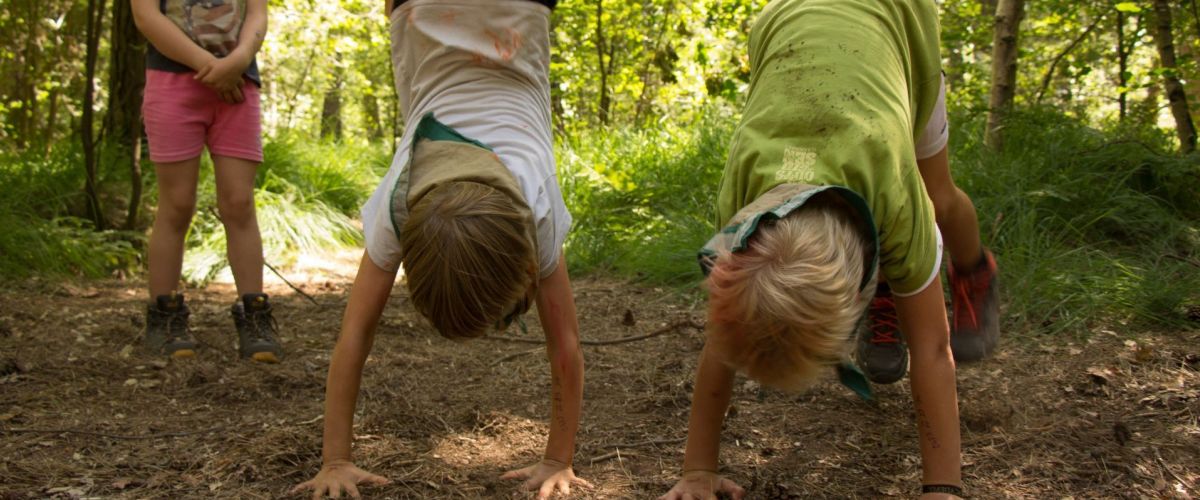 in het bos doen 2 kapoenen handstand een derde kijkt toe