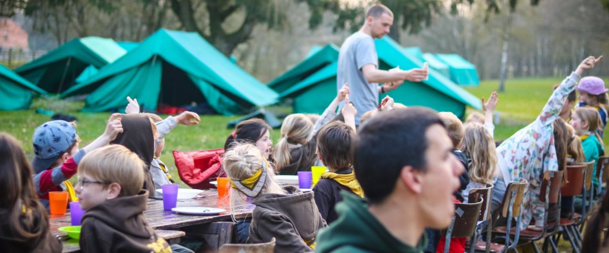 Kinderen aan tafel met tenten op de achtergrond