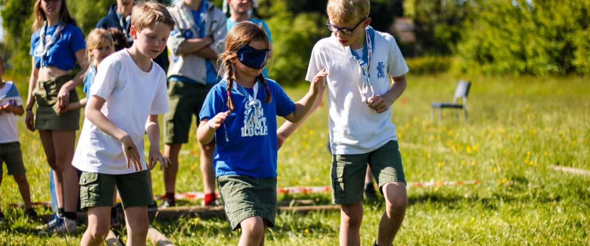 twee welpen begeleiden een geblinddoekte welp