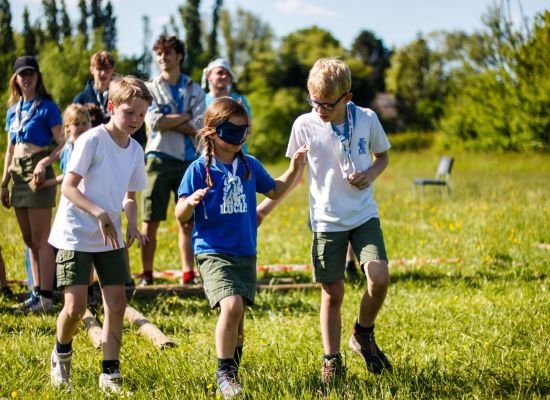 twee welpen begeleiden een geblinddoekte welp